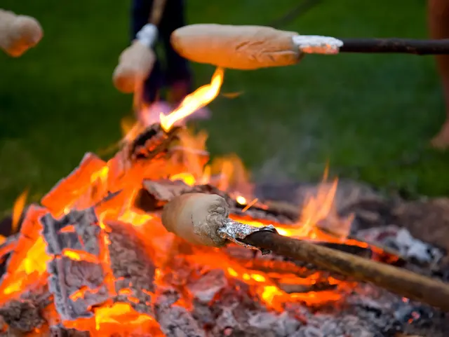 Lagerfeuer und mehrere Stöcke mit Stockbrot darüber