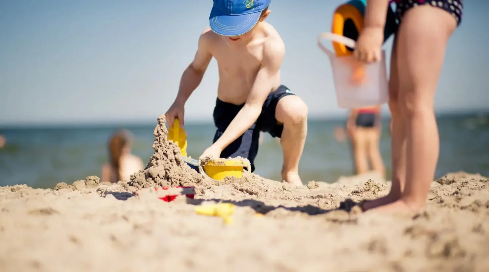 Buddelspaß am Strand – Familienurlaub auf Fehmarn Ein Kind buddelt im Sand am Meer während des Familienurlaubs auf Fehmarn.