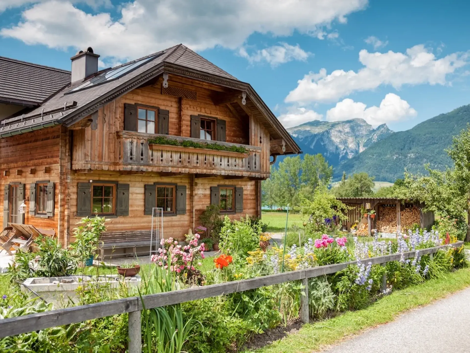 Traditionelles Ferienhaus auf dem Bauernhof in den Alpen - © and.one, adobe stock Traditionelles Holzhaus im Alpenstil steht auf einem Bauernhof inmitten grüner Berglandschaft – typisches Ferienhaus auf dem Land für naturnahen Urlaub in den Bergen.