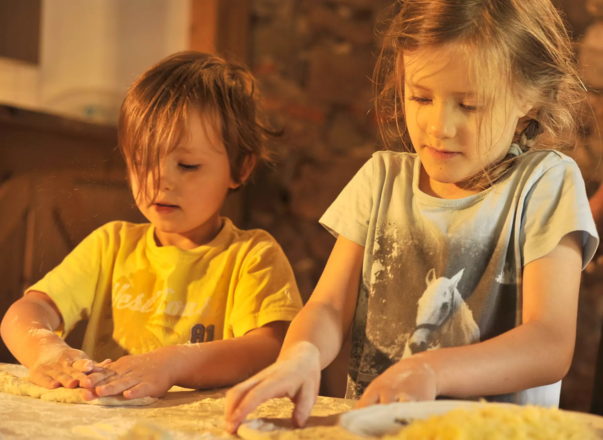 im Urlaub auf dem Kinderhof backen Kinder mit der Bäuerin Pizza und Brot