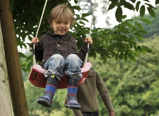 im Urlaub auf dem Kinderhof toben Kinder auf dem Spielplatz