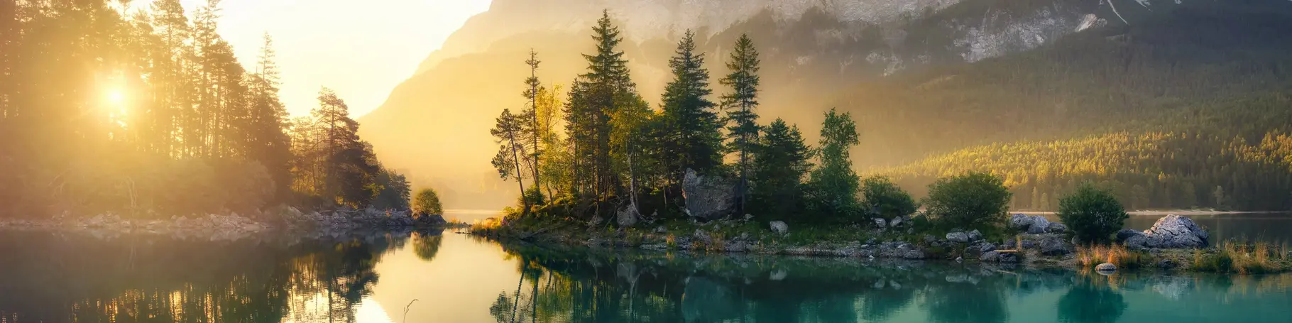 Idyllischer See bei Sonnenaufgang, ein malerisches Panorama mit majestätischen Bergen und dem goldenen Sonnenlicht, das hinter den Bäumen hereinscheint