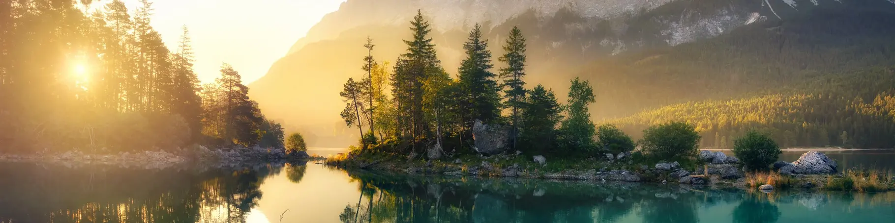 Idyllischer See bei Sonnenaufgang, ein malerisches Panorama mit majestätischen Bergen und dem goldenen Sonnenlicht, das hinter den Bäumen hereinscheint