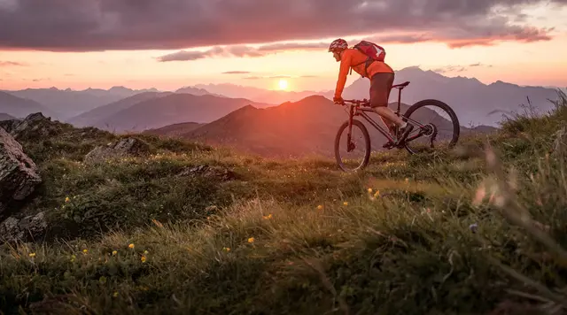 Fahrradfahren in ländlicher Landschaft im Sonnenuntergang - © mRGB, adobe stock Person fährt Fahrrad in ländlicher Landschaft bei Sonnenuntergang