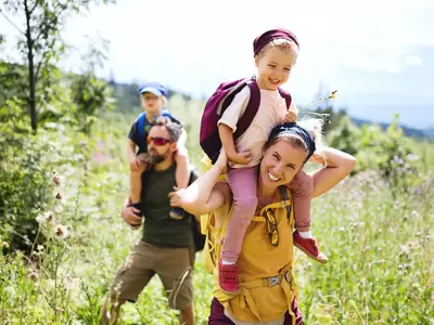 Vorderansicht einer Familie mit kleinen Kindern beim Wandern im Freien in der sommerlichen Natur.