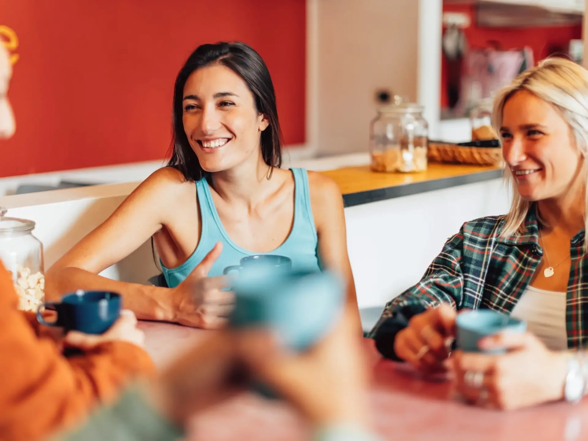 Camping auf dem Bauernhof: Gemeinschaftsräume - © Carlo Prearo, adobe stock Gruppe von Personen sitzt am Tisch in einem Gemeinschaftsraum und unterhält sich fröhlich.