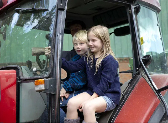 im Urlaub mit Kindern auf dem Bauernhof in Schleswig-Holstein auf dem Traktor mitfahren