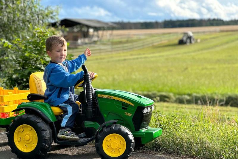 Junge auf dem Kindertraktor entdeckt den Hof